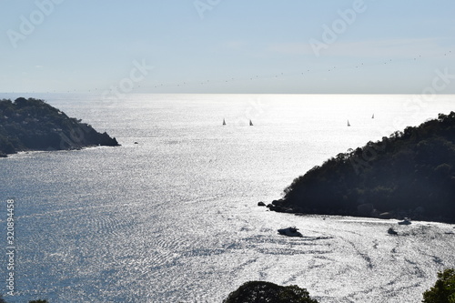 Reflejos del sol en el mar de la bahia de Pichilingue Acapulco, y siluetas de barcos y veleros