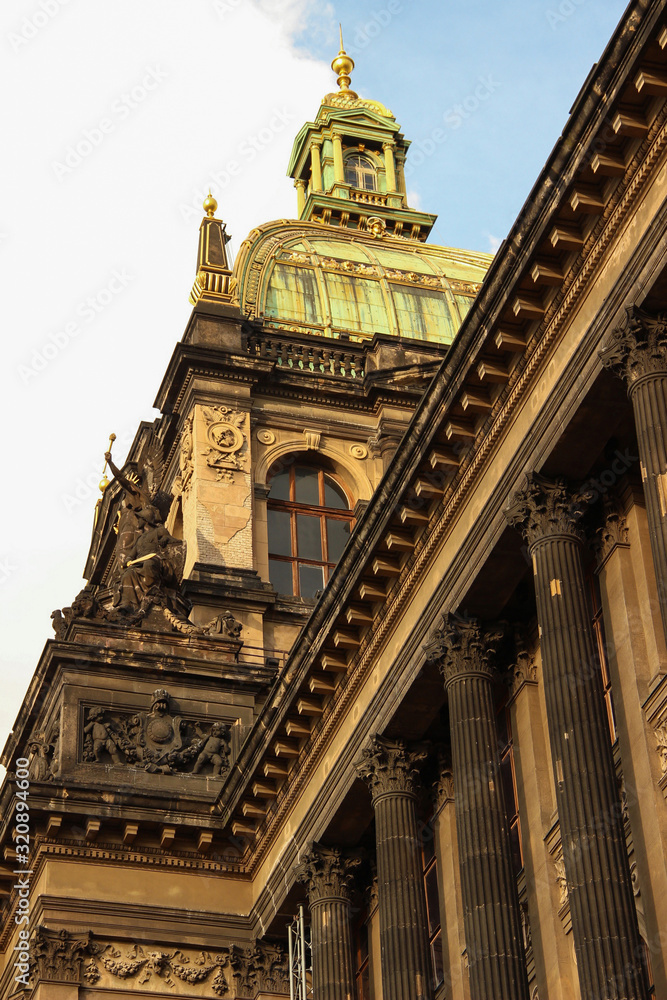 Close-up of an old building. Front facade of the main building with columns, statues and dome during the sunset. Prague, Czech Republic.