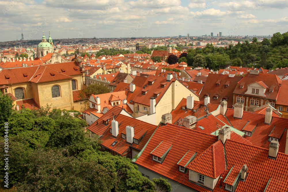 Obraz premium Roofs of houses, buildings and St. Nicholas Church dome. Skyline and Schönborn Garden. View from Prague Castle (Pražský hrad).