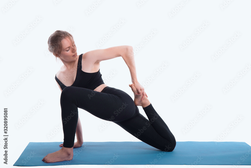Young beautiful woman practicing yoga, on white background, and doing some stretching exercises by sitting.