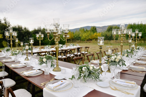 Fototapeta Naklejka Na Ścianę i Meble -  Decorated wedding celebration table with guests seats outdoors in the gardens with a mountain view