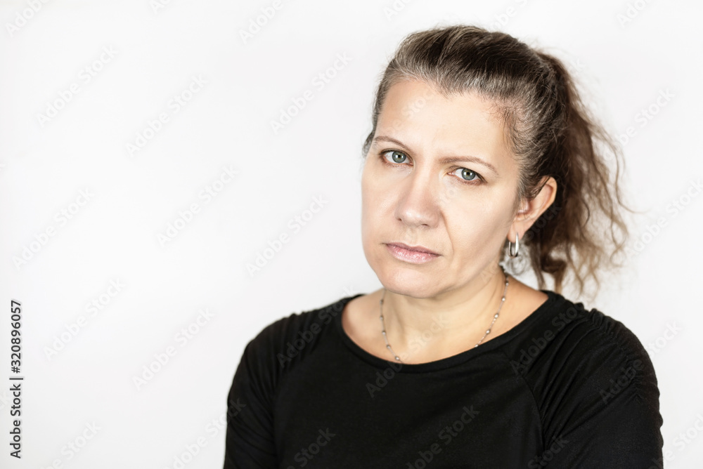 Beautiful middle-aged woman with a sad face on a light background, her hair begins to turn gray so she is not happy, it is time to dye her hair Beautiful middle-aged woman with a sad face on a light background, her hair begins to turn gray so she is not happy, it is time to dye her hair