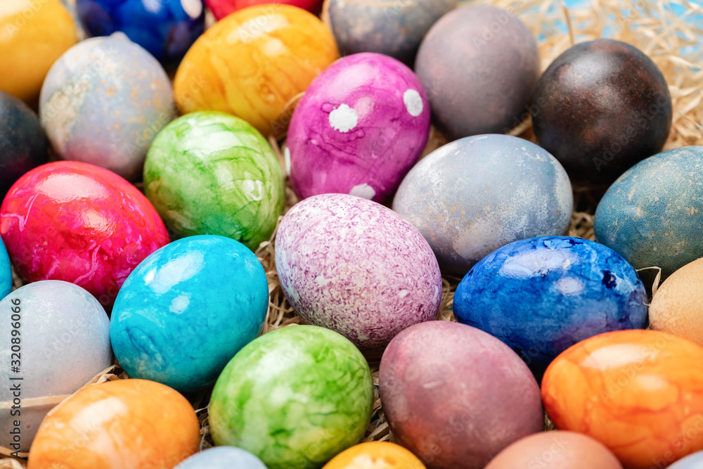 Different easter eggs with straw on wooden plate on green table Different easter eggs with straw on wooden plate on green table
