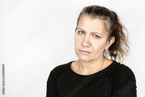 Beautiful middle-aged woman with a sad face on a light background, her hair begins to turn gray so she is not happy, it is time to dye her hair
