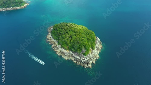 Nice rocks forested island, aerial panorama of Ko Pu against mountainous Phuket landscape on background. Deep tropical jungle thicket covering stony islend.Boat sailing. Aerial photo