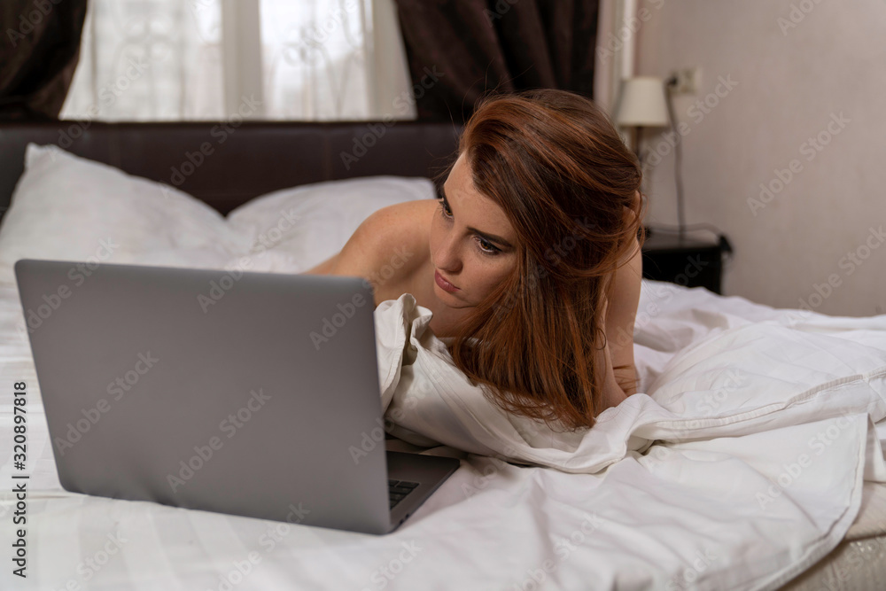 girl in white panties lies on the bed and looks at the laptop girl in white panties lies on the bed and looks at the laptop