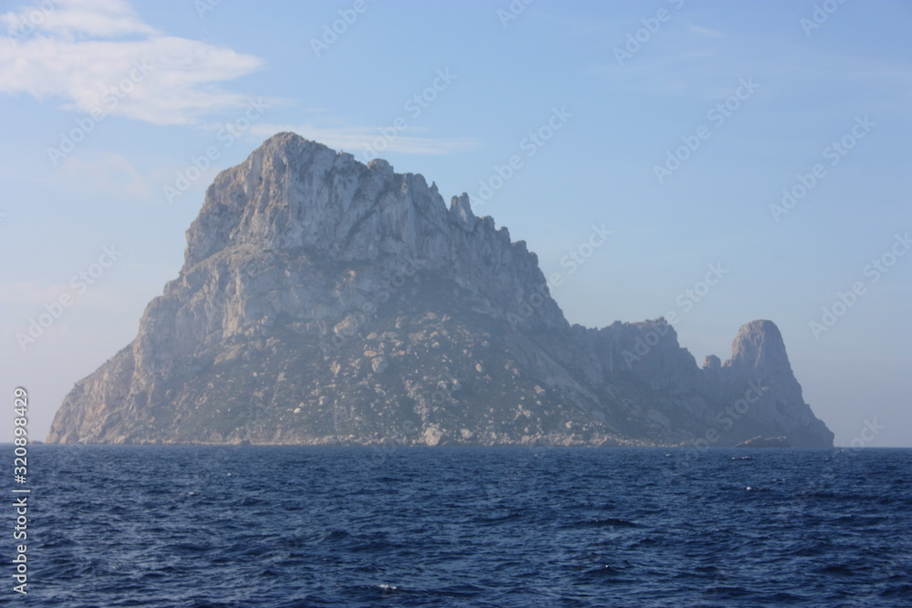 the islet of Es Vedra among the mist on the blue water of the ibiza sea