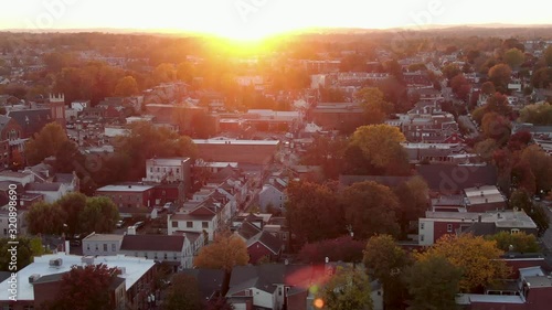 Golden sunset over urban city, colorful fall leaves, foliage line street in residential neighborhood community, aerial drone footage photo