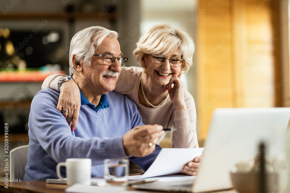 © Drazen - Happy mature couple using laptop while planning their home budget.