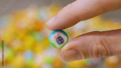 Hand holding colorful candy with a gift on it. candies in the background photo