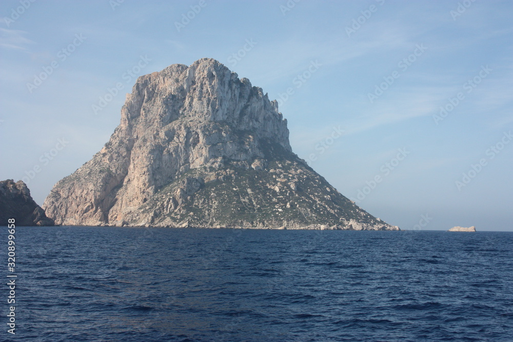 the islet of Es Vedra among the mist on the blue water of the ibiza sea