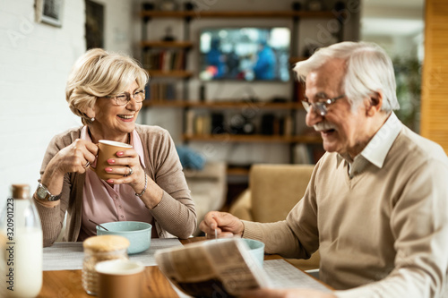 Happy senior woman drinking coffee and talking to her husband during breakfast.