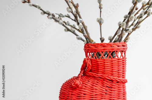 Still life with catkins in creative red wicker vase. Spring symbol, selective focus.
