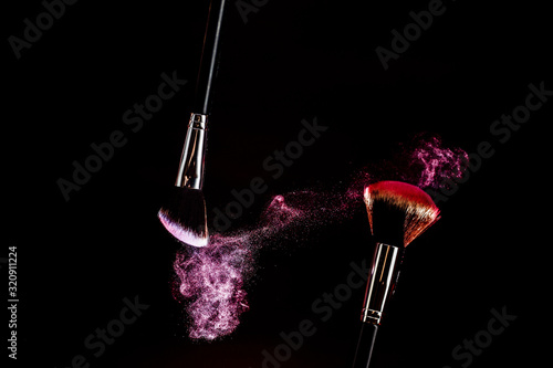Makeup brushes. Pink spray. Pink dust. Beautiful effect.