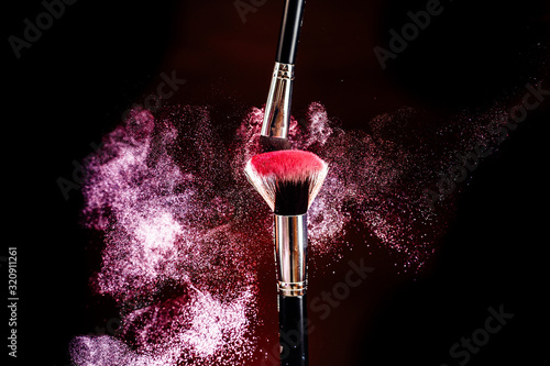 Makeup brushes. Pink spray. Pink dust. Beautiful effect.