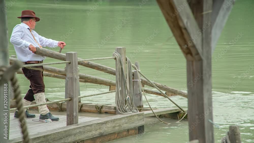 A slow motion of a man guiding the wooden raft on the Drava river. A slow motion of a man guiding the wooden raft on the Drava river.