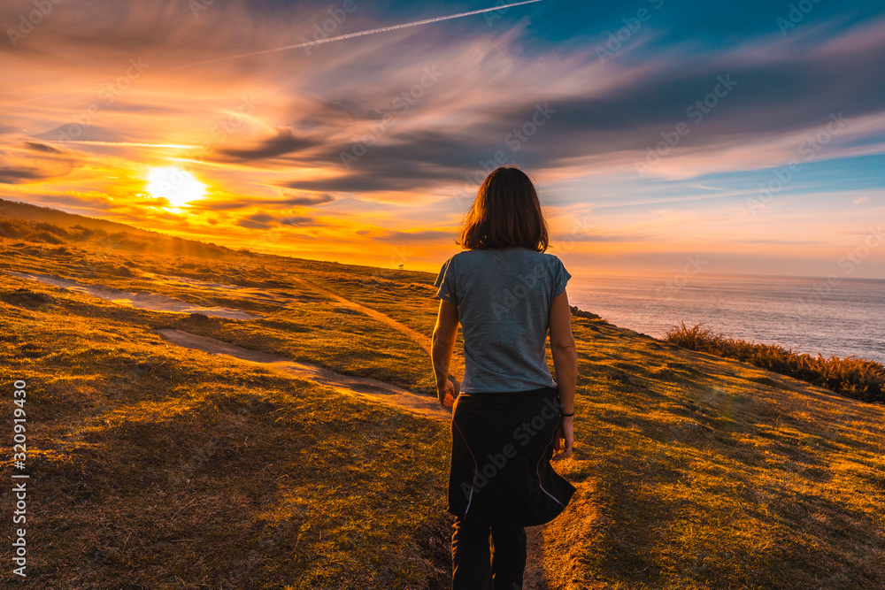 A young woman walking in the sunset along the path of Mount Jaizkibel. Basque Country