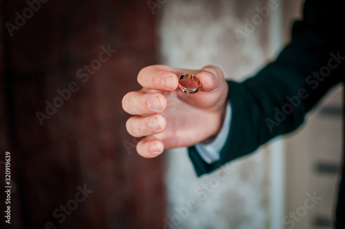 Groom holding golden wedding rings on the hand