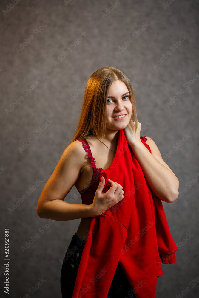 Girl tries on a red sweater on a gray background Girl tries on a red sweater on a gray background