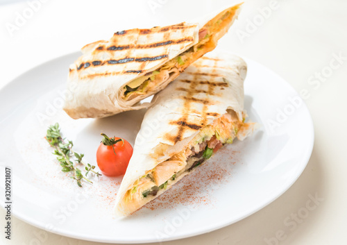 Sliced pita grilled on a white plate with tomato and marjoram