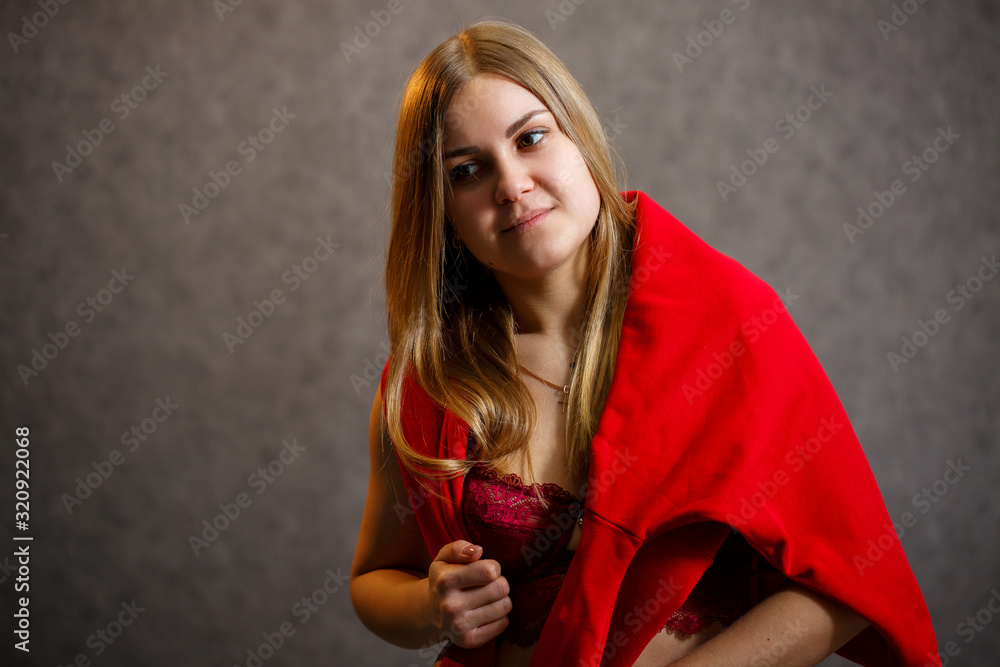 Naklejka premium Girl tries on a red sweater on a gray background