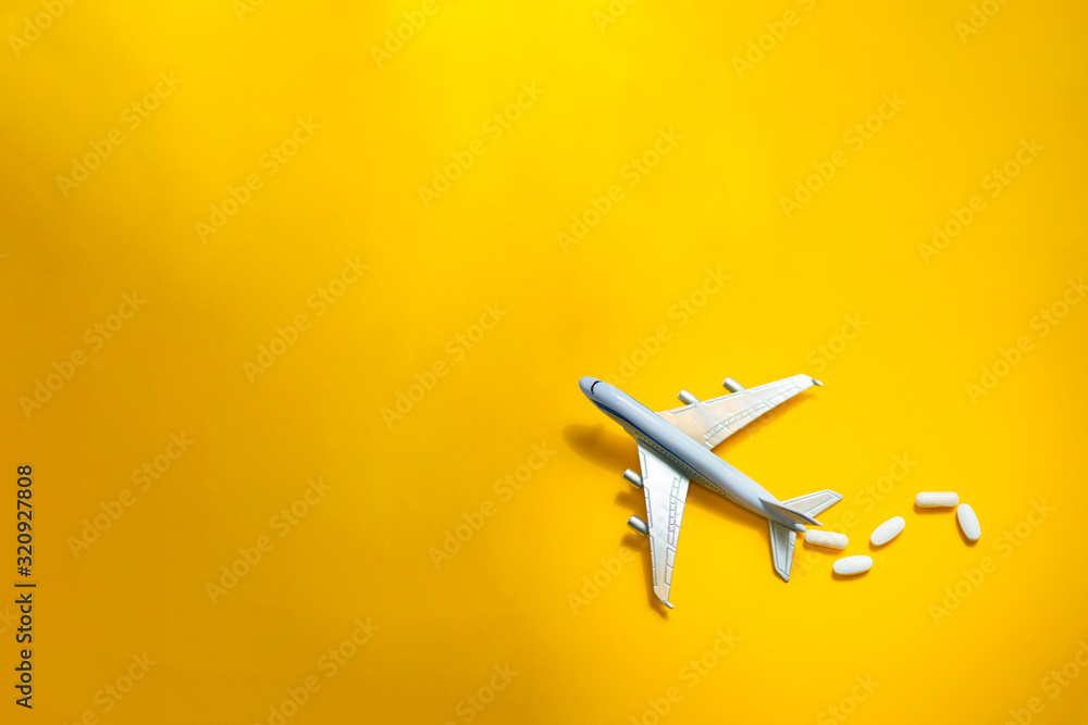Plane figurine with pills spilled. Travel and medicine concept. Flat lay view with copy space on minimalist gray background. - obrazy, fototapety, plakaty 