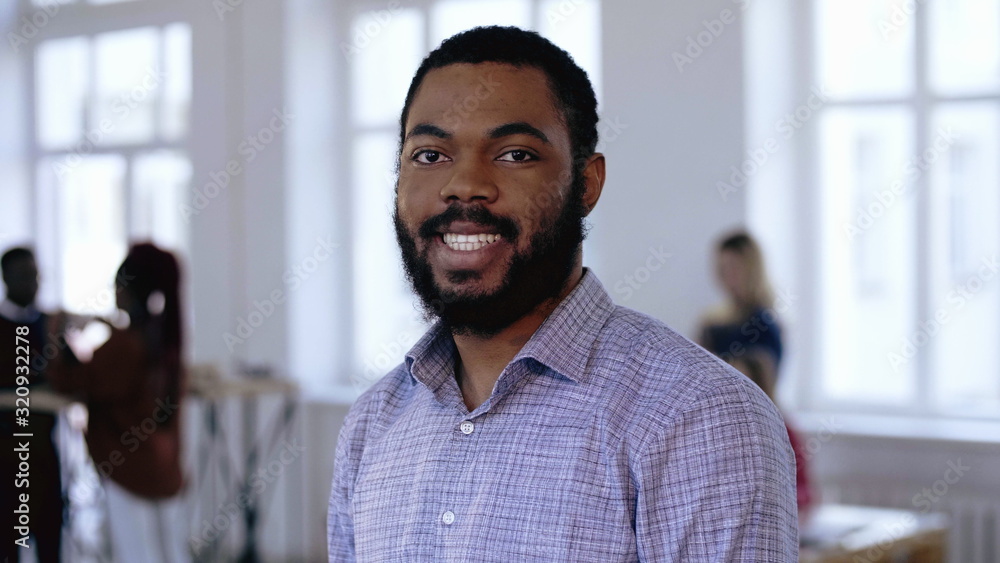 Obraz premium Portrait of happy professional black entrepreneur businessman with beard and beautiful smile posing at modern office.