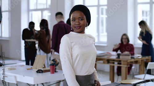 Photo Happy smiling young successful African entrepreneur business woman wearing turban smiling at modern light loft office