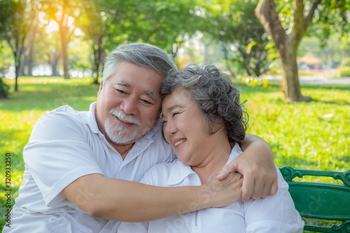 Romantic senior couple. Elderly man or Senior asian husband embracing senior wife. Lovely elderly couple talking about their life, smiley faces at park. Old man and old woman love each other so much