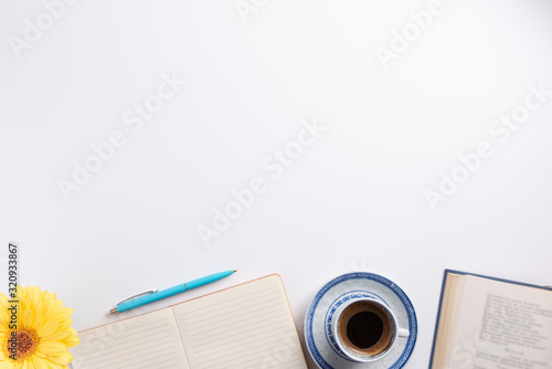 Workplace with open books and cup of coffee. Cup of coffee, flower, notebook, isolated on white background. Flat lay, top view, copy space.