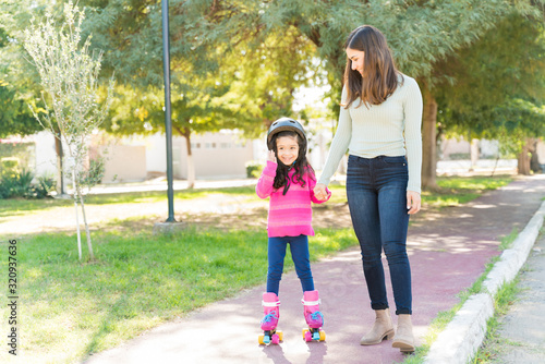 Fototapeta Naklejka Na Ścianę i Meble -  Smiling Girl Learning To Skate From Mother