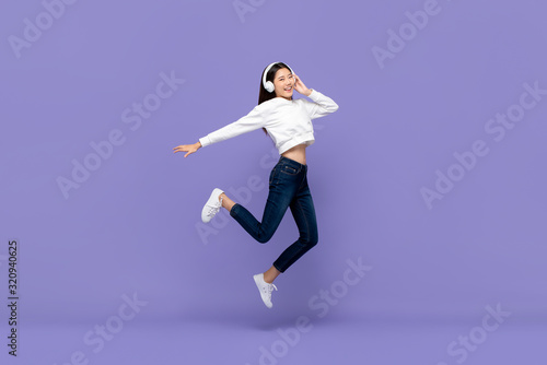Asian woman jumping and listening to music on headphones photo