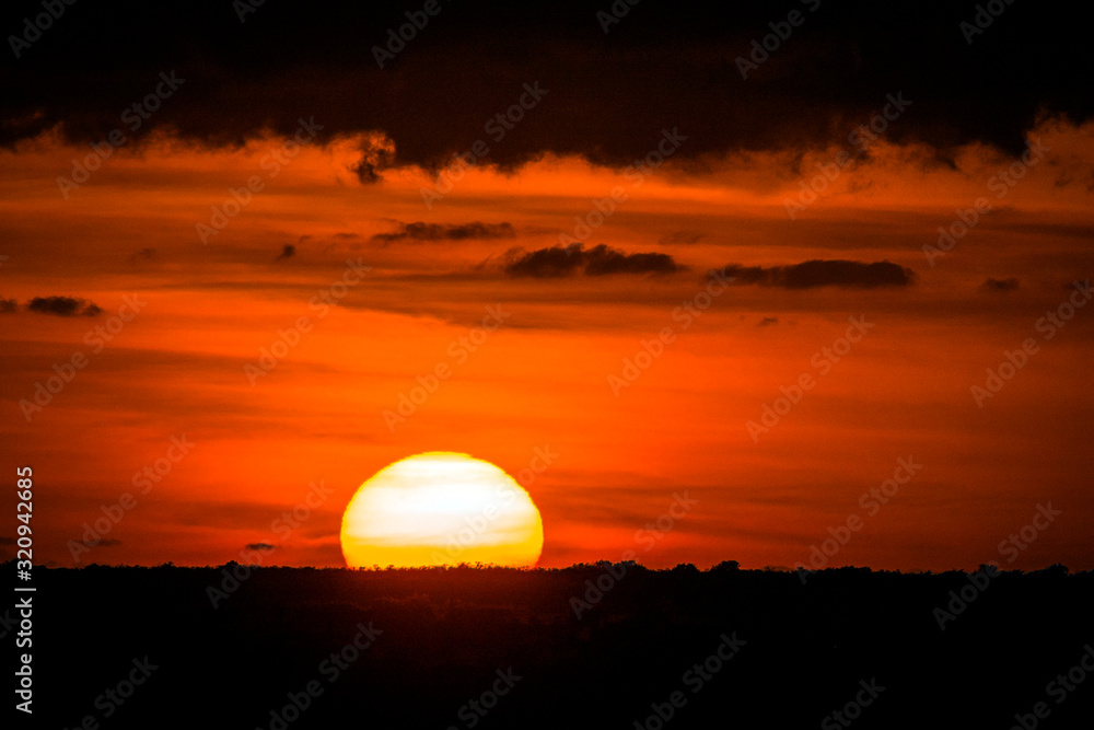 Large sunset on horizon with fiery sky and dark clouds
