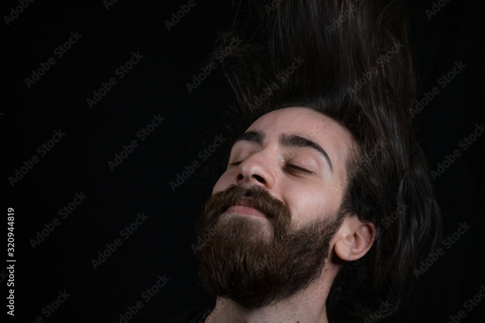 Fototapeta premium Hipster teenager man hair tossing, black isolated background.