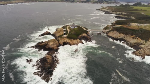 Wide aerial shot captured by a drone from the top of the Pancha Island and its beautiful lighthouse, in Ribadeo, Galicia, Spain. photo