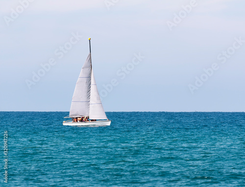 A sailboat with a crew in life jackets is floating in the sea