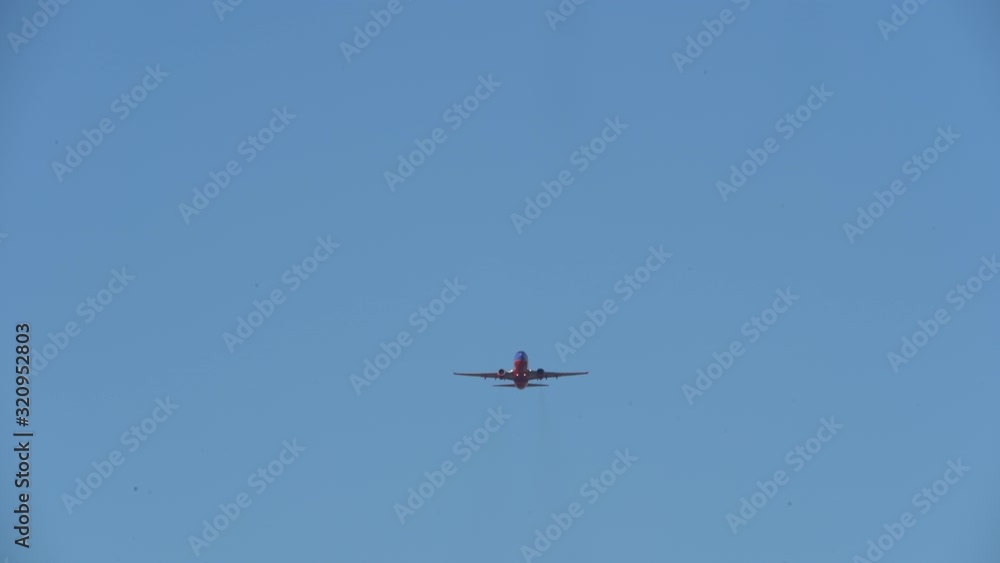 Red and Blue Airplane Flying Through the Sky Toward Arrival at Destination Red and Blue Airplane Flying Through the Sky Toward Arrival at Destination