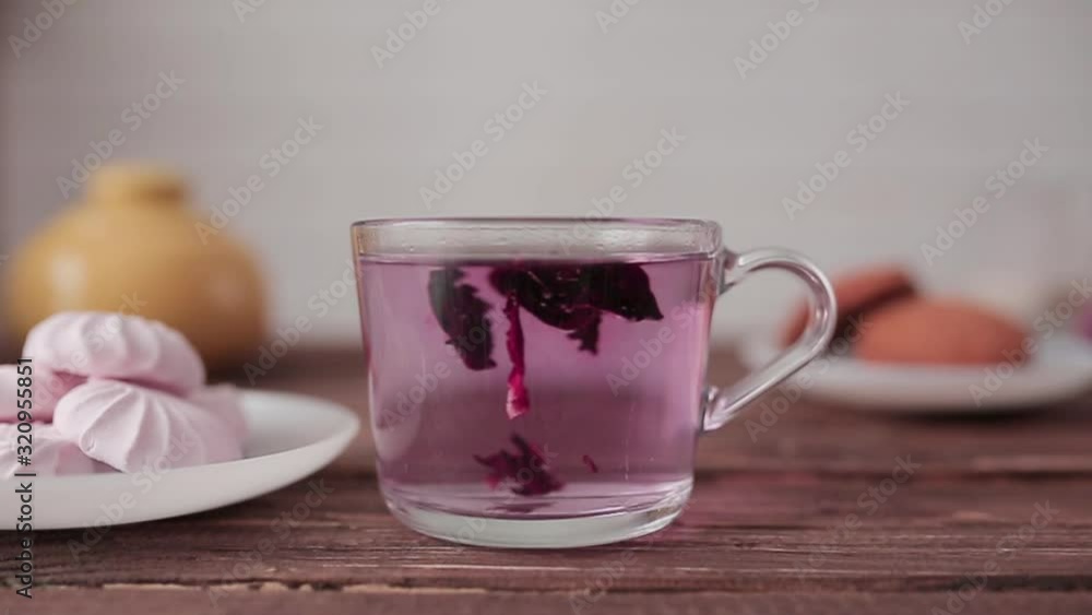 Hibiscus red tea is brewed in a cup on a wooden table. Hibiscus red tea is brewed in a cup on a wooden table.