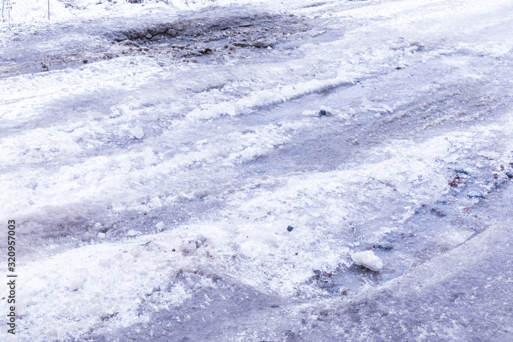 The bad asphalt winter road or way with ice, snow, puddles, pools, mud and slush The bad asphalt winter road or way with ice, snow, puddles, pools, mud and slush
