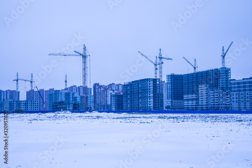 The skyscraper building construction in the new block in the city suburb or downtown in the field in the winter cold and frost coudy weather with ice and snow