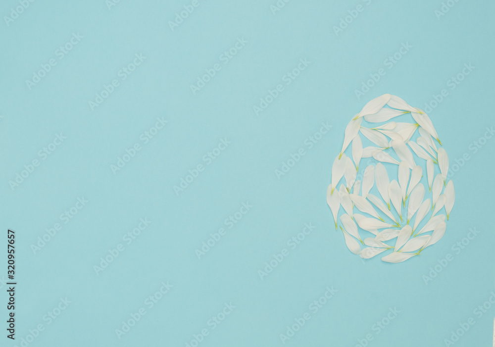 Easter egg made of white flower petals on blue background. Happy Easter holiday concept. Concept of minimalism. Greeting card. Flat lay style with copy space. Easter egg made of white flower petals on blue background. Happy Easter holiday concept. Concept of minimalism. Greeting card. Flat lay style with copy space.