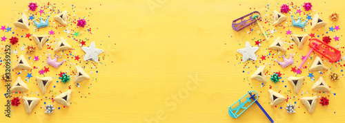 Purim celebration concept (jewish carnival holiday) over yellow wooden background. Top view, Flat lay photo