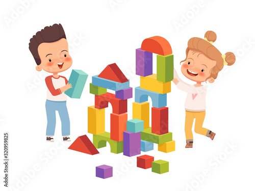 Boy and girl are smiling and building a tower of children's blocks. Children play friendly and fun together