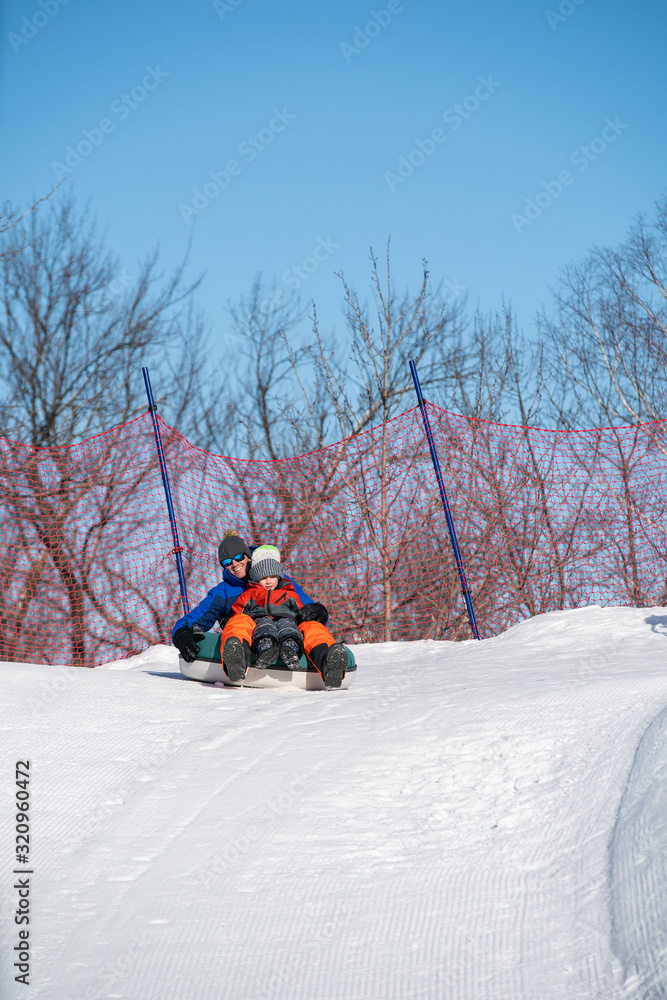 Father and son snow tubing in the winter in Canada