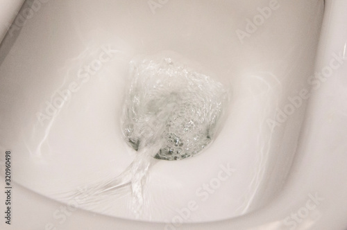 Water drains in a white toilet close-up. Plumbing Design