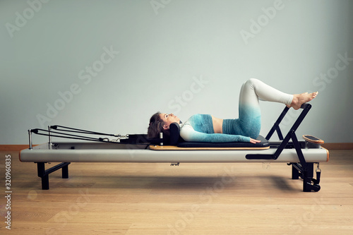 leotard workout pilates training. athletic pilates reformer exercises. pilates machine equipment. young asian woman pilates stretching sport in reformer bed instructor girl in a studio photo