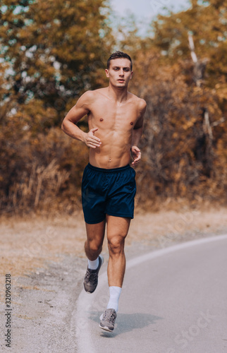 Runner athlete running on forest trail. Man fitness jogging workout wellness concept