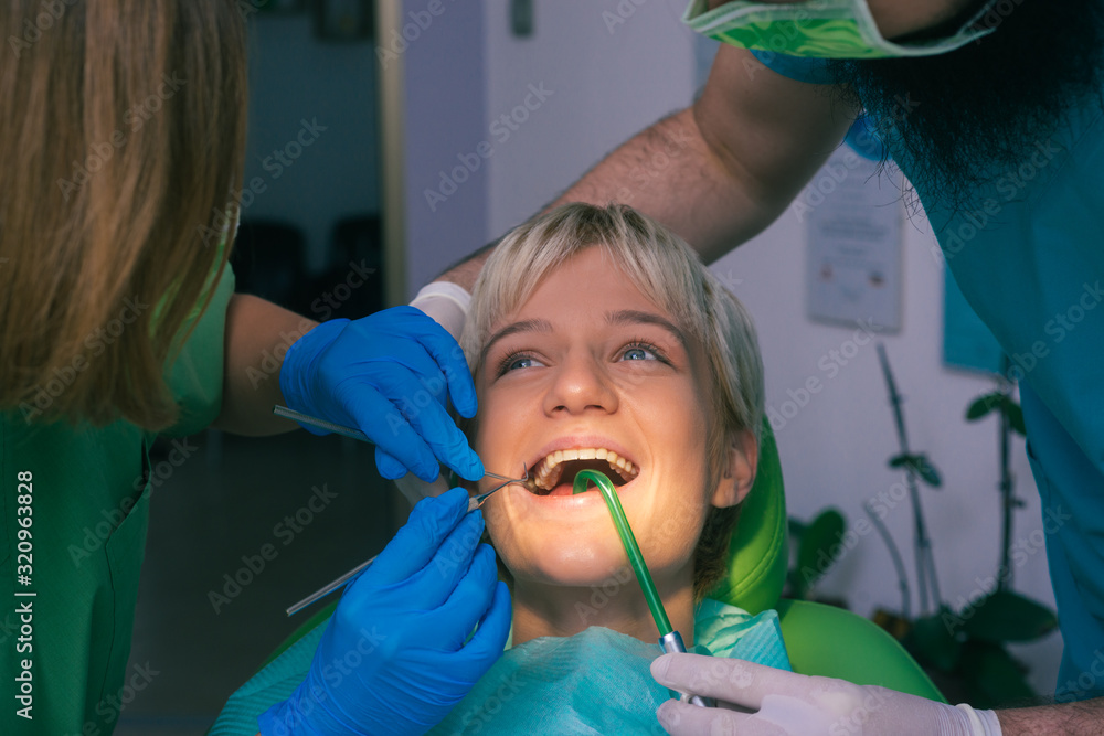 Dentist in green uniform examining the teeth of a beautiful female patient Dentist in green uniform examining the teeth of a beautiful female patient