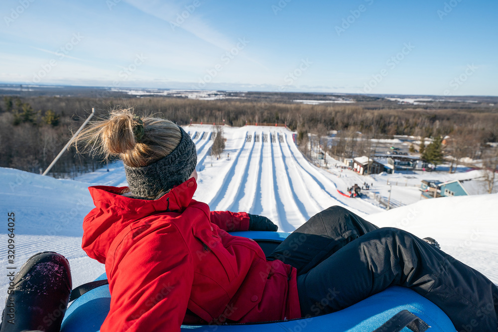 Beautiful woman snow tubing in the winter in Canada