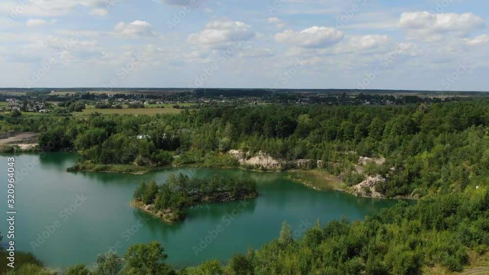 Aerial View of a lake with Beautiful Water in a Quarry Surrounded by Forest, Small Town and Mining Operation Tracking Forward Toward Water Aerial View of a lake with Beautiful Water in a Quarry Surrounded by Forest, Small Town and Mining Operation Tracking Forward Toward Water